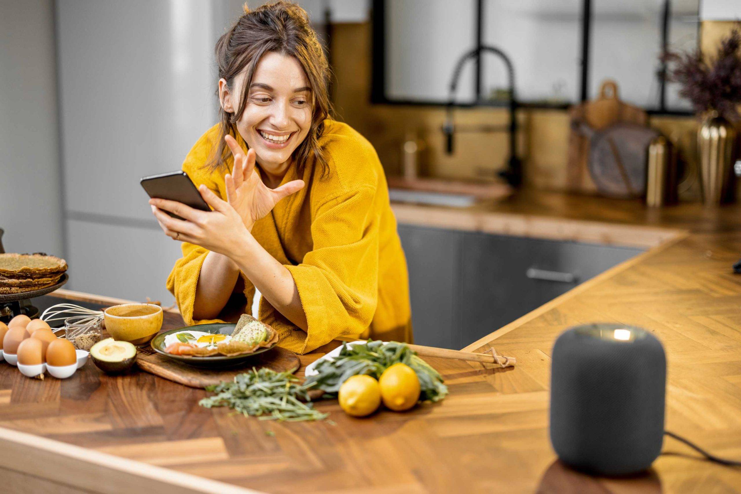 Woman using voice-enabled smart speakers in kitchen