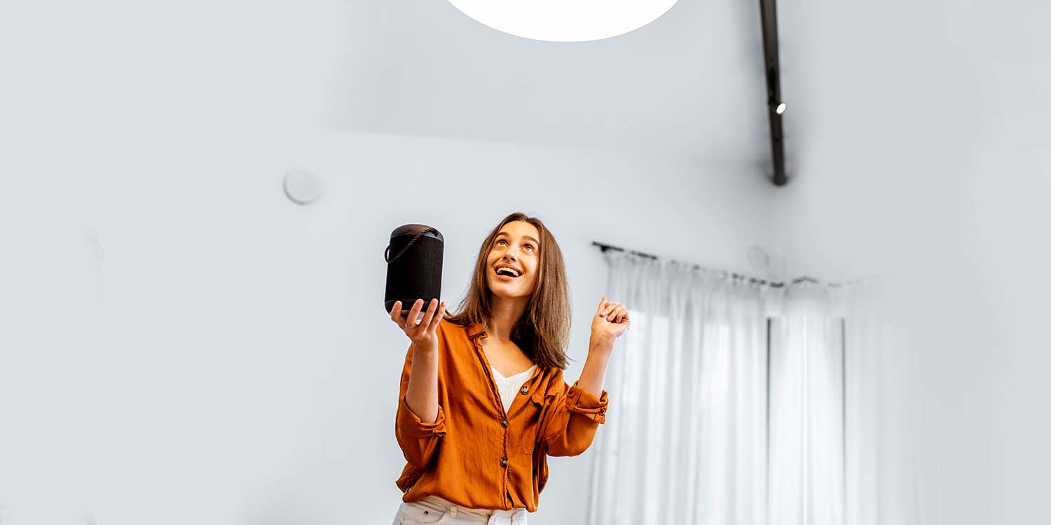 Woman Switching on lights using voice-enabled smart speaker