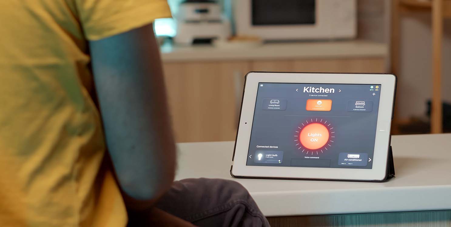 Man turning on kitchen lights with voice intelligent tablet